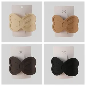 Dettaglio di quattro fermagli per capelli a fiocco opaco in beige, marrone e nero