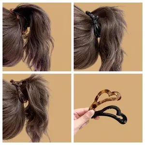 Dettaglio di fermagli per capelli a cuore vuoto tartarugati e neri su una coda