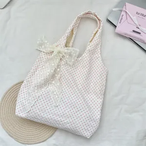 Detailed view of large white lace bow on a pink polka dot canvas shoulder bag for women