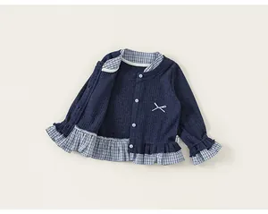 Close-up detail of girls' navy knit jacket featuring plaid ruffle hem and bow accent