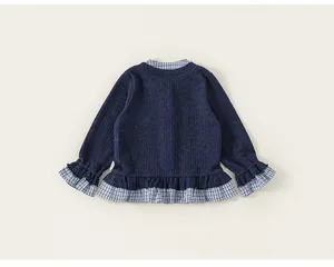 Detailed view of the plaid ruffle hem and collar on the navy blue girl's top
