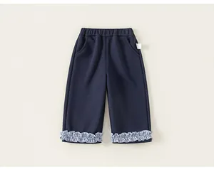 Detail view of navy blue girls' pants with ruffled plaid hem and elastic waist.