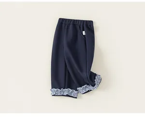 Close-up detail of navy blue children's pants featuring checkered ruffle cuffs and waist