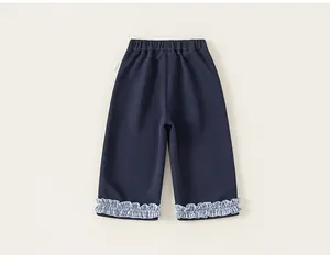 Detail view of navy blue girl's trousers featuring plaid ruffle hems and elastic waist
