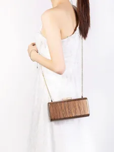Detailed macro view of a brown acrylic shell evening bag with golden metal chain strap