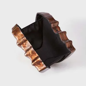 Detail view of brown tortoiseshell acrylic evening clutch with wave texture and black lining
