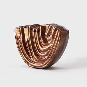 Macro detail of U-shaped amber acrylic evening bag with deep vertical pleat textures