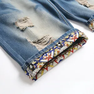 Distressed blue denim shorts with ripped details and luxury chain pattern lining