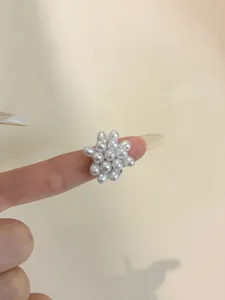 Detail of vintage square pearl ring cluster on a finger with silver glitter nails