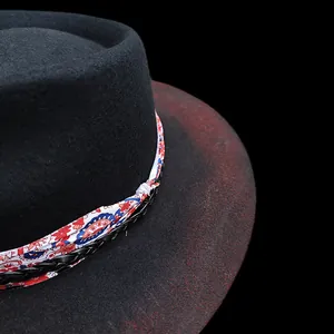 Détail d'un chapeau fedora en laine noire avec ruban floral ethnique et cordon en cuir