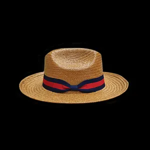 Detail of natural straw hat texture with navy and red striped grosgrain ribbon bow