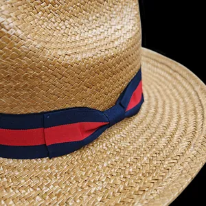 Close-up of woven straw hat featuring classic red and blue striped ribbon detail
