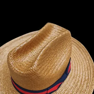 Detailed view of woven straw cowboy hat featuring red and blue striped ribbon band
