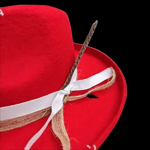 Detalle de sombrero de lana rojo con cinta blanca, cuerda de cáñamo y pluma moteada