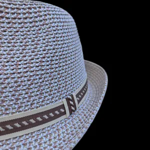 Close-up of woven straw fedora hat featuring detailed texture and geometric striped band