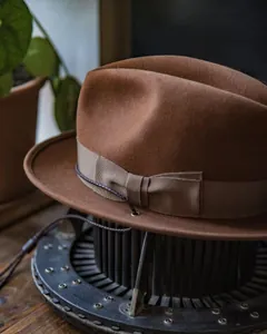 Detail view of brown wool fedora with ribbed band, metallic eyelets and braided cord