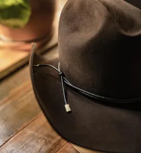 Detalle de sombrero vaquero de fieltro marrón con banda de cuerda y puntas de plata