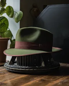 Detail of dark green wool felt fedora featuring a classic brown grosgrain ribbon band