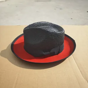 Detail of fedora hat with black straw crown, red underbrim, and grosgrain bow ribbon