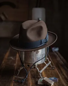 Detail view of dark brown wool fedora with black ribbon and adjustable chin strap