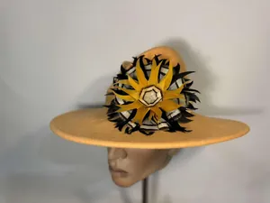 Detail of elegant camel wool fedora featuring a vibrant radial feather ornament