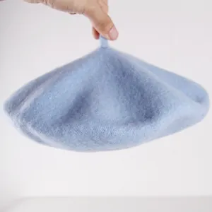 Detail of light blue wool beret featuring textured fabric and classic top stem design