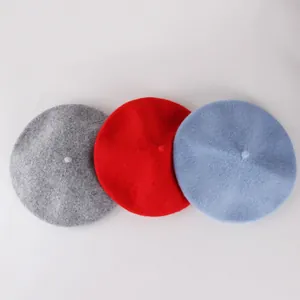 Flat lay of wool beret hats in grey red and light blue colors on white background