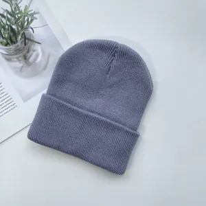 Détail de la texture d'un bonnet en maille côtelée bleu-gris sur fond minimaliste