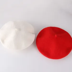 Detail view of red and white wool beret hats with classic stalk tops for children