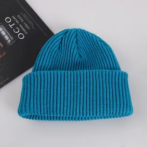 Close-up of thick ribbed knit texture on a peacock blue beanie with folded brim