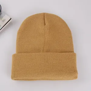 Detail of solid color knitted beanie featuring ribbed texture and wide folded brim for winter