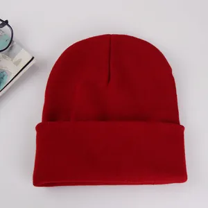 Detailed knit texture of solid red cuffed beanie hat on a clean white background