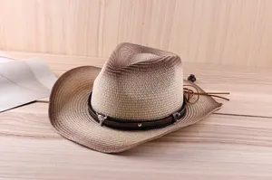 Detail of woven straw cowboy hat featuring bull skull emblem and brown leather strap