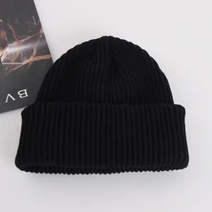 Close-up of thick ribbed knit texture on a black winter beanie with a stylish background
