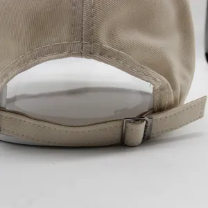 Detalle de la gorra de algodón beige con hebilla metálica ajustable en la parte trasera