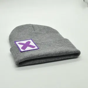 Detailansicht der grauen Strickstruktur und violetten X-Grafik am Mützenaufschlag