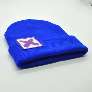 Makro-Detail der gerippten Strickmütze mit violettem X-Patch auf blauem Stoff