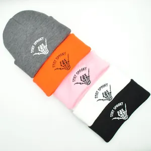 Detailed embroidery of Stay Spooky text and skeleton hand on colorful knit beanies