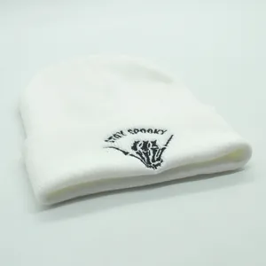 Close-up of Stay Spooky embroidery and skeleton hand on a white knitted beanie hat