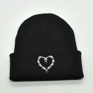 Close-up of heart embroidery with barbed wire pattern on black knitted beanie hat