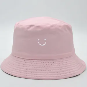 Cappello da pescatore in cotone rosa con ricamo smiley bianco su fondo bianco