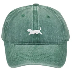 Vintage washed green baseball cap with embroidered dog silhouette on plain background