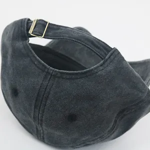 Close-up of adjustable strap with bronze metal buckle on washed charcoal denim baseball cap