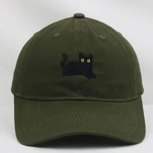 Primo piano del ricamo di gatto nero con occhi gialli su berretto di cotone verde oliva
