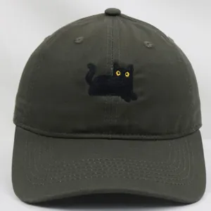 Dettaglio del ricamo a gatto nero con occhi gialli su un cappellino in cotone verde
