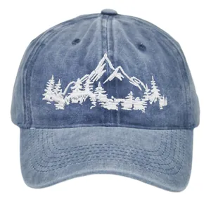 Detail of mountain forest embroidery on washed blue cotton baseball cap with white thread