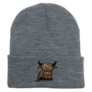 Detailed close-up of dark grey knitted beanie featuring a highland cow embroidery