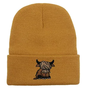 Close-up of mustard yellow knit beanie featuring a highland cow embroidery detail