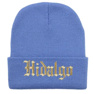 Dettaglio del ricamo dorato Hidalgo su un berretto in maglia blu con bordo risvoltato