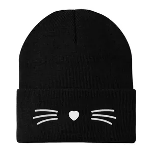 Dettaglio del ricamo a gatto bianco con cuore su un berretto in maglia nera invernale